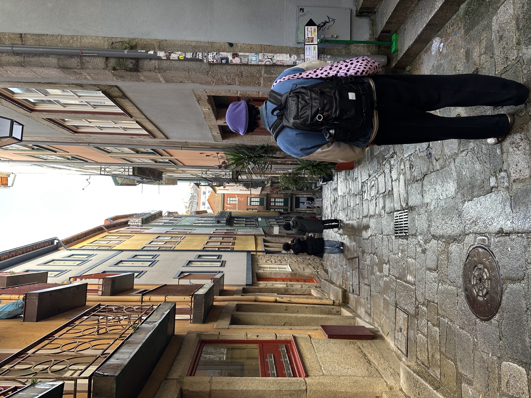 Nate with a backpack and camera walking down a narrow cobbled alley in Porto